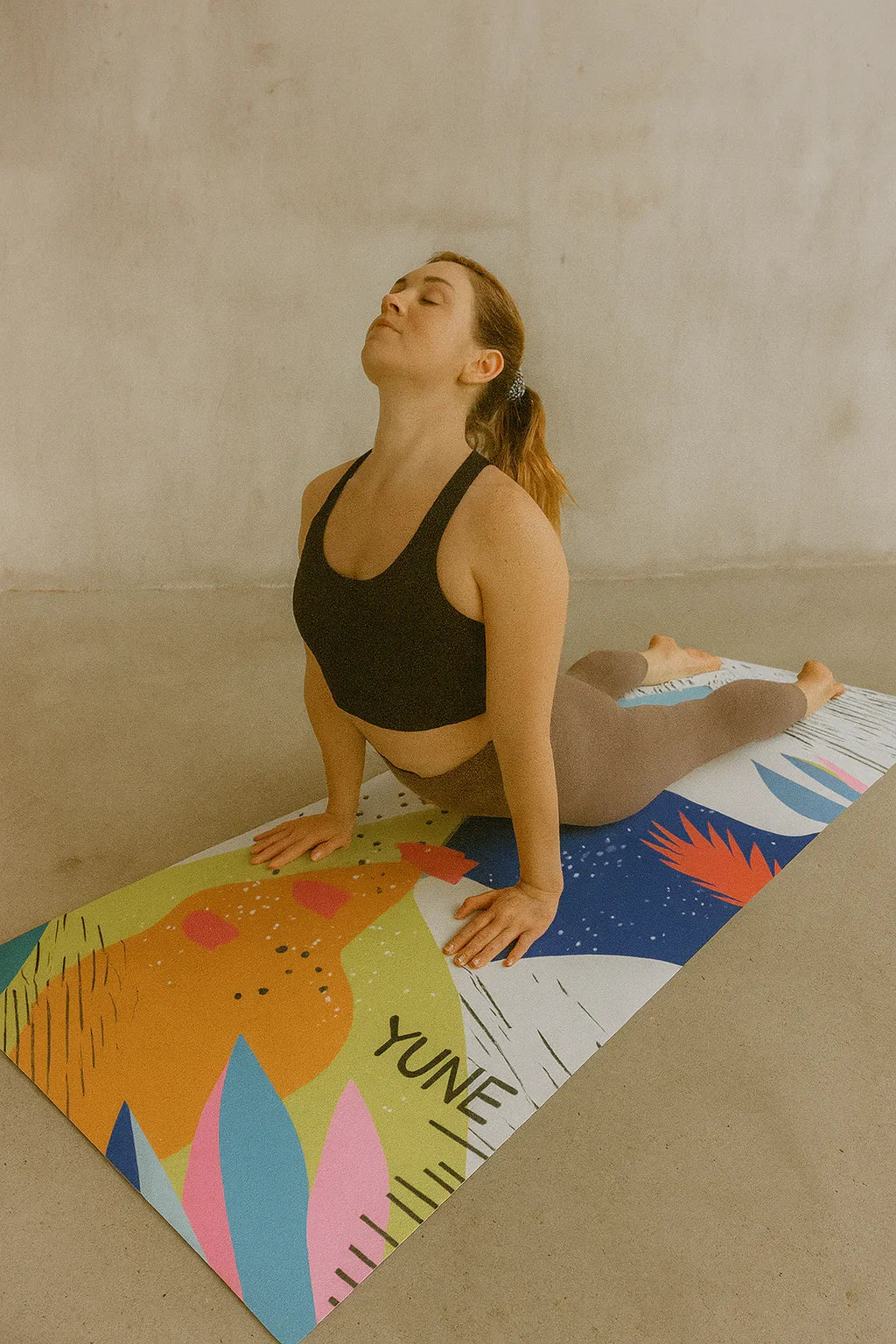Woman practicing yoga on a colorful mat with a neutral background