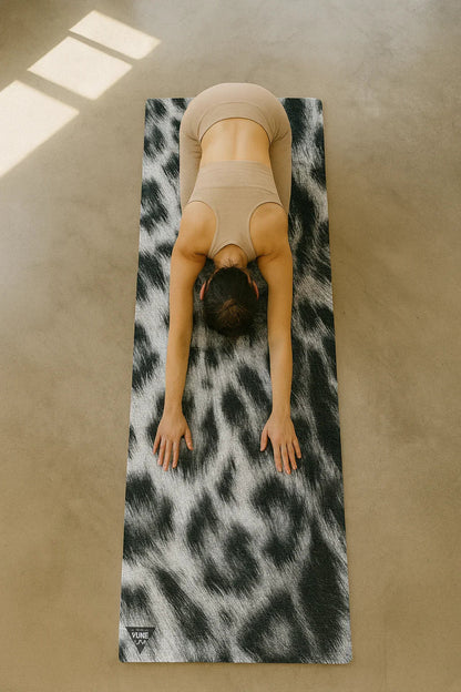 Person practicing yoga on a leopard print mat in a sunlit room