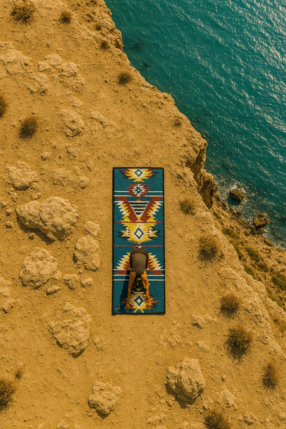 Person sitting on a colorful patterned rug by the ocean