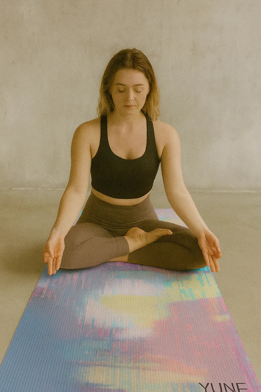 Woman practicing yoga on a colorful mat with a neutral background