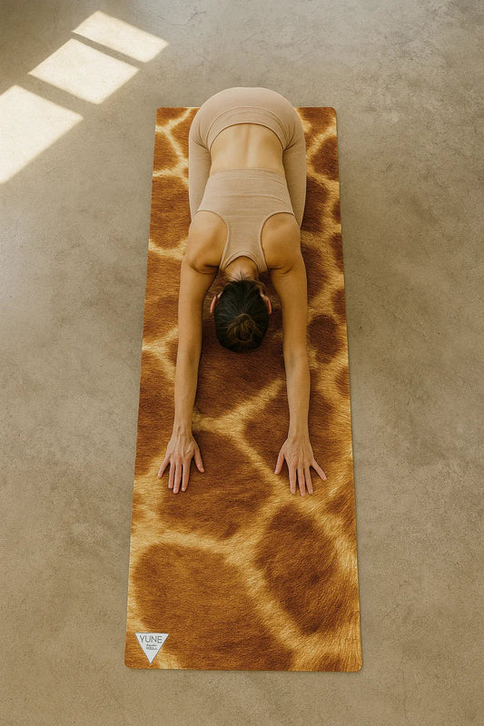 Person practicing yoga on a giraffe-patterned mat in a sunlit room.