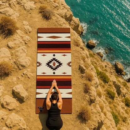 Person practicing yoga on a patterned mat by the ocean