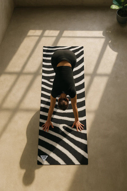 Person practicing yoga on a black and white striped mat with a plant in the corner.