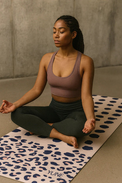 Woman meditating on a leopard print yoga mat with a neutral background