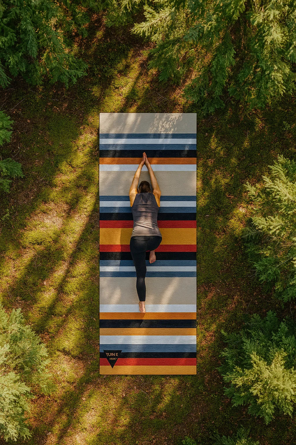 Person practicing yoga on a striped mat in a forest