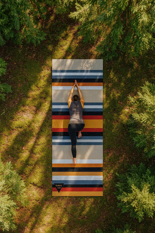 Person practicing yoga on a striped mat in a forest