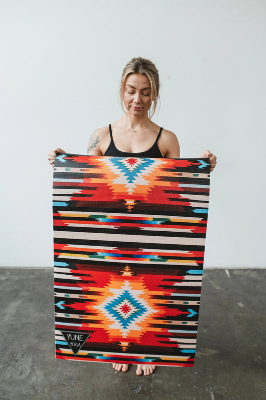Woman holding a colorful patterned blanket with a geometric design.