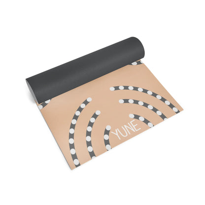 Yoga mat with black top and beige bottom featuring a pattern and the brand name 'YUNE'.