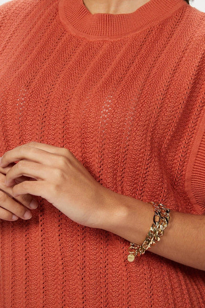 Rust-colored knit top paired with Axel Bracelet featuring a gold chain design