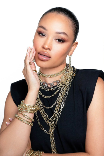 Woman wearing multiple gold chains and bracelets with the Dean Lariat Necklace style