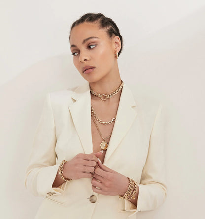 Woman showing off Roxy Bracelet with gold jewelry and a white blazer