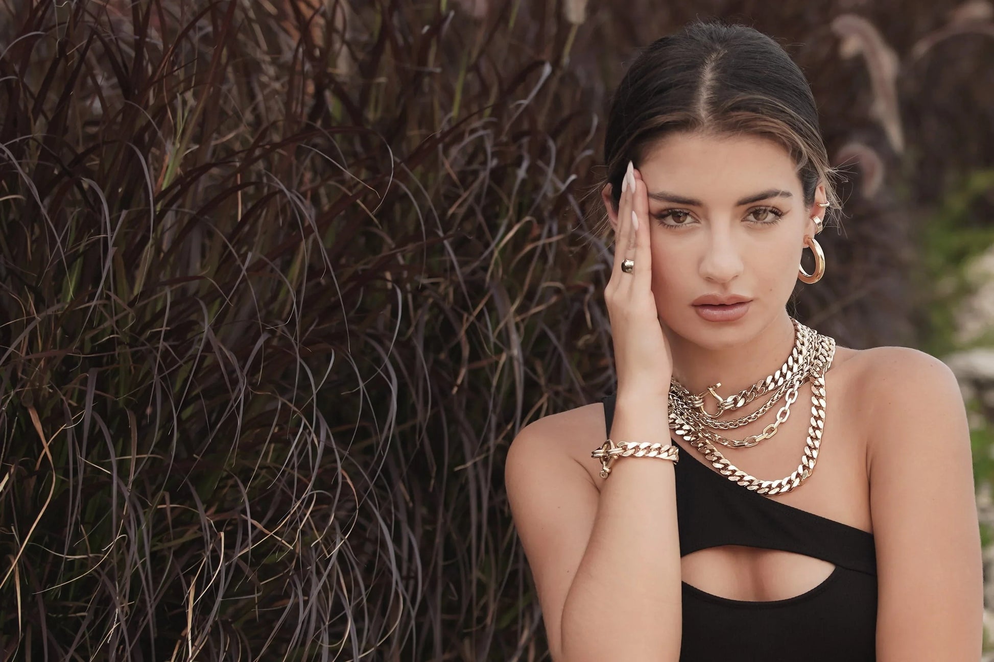 Woman wearing layered gold chains on the Roxy Bracelet jewelry product