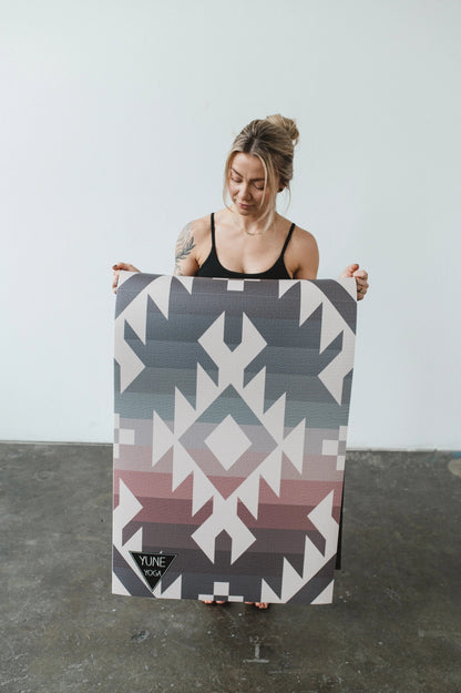 Person holding a large geometric-patterned board against a plain background